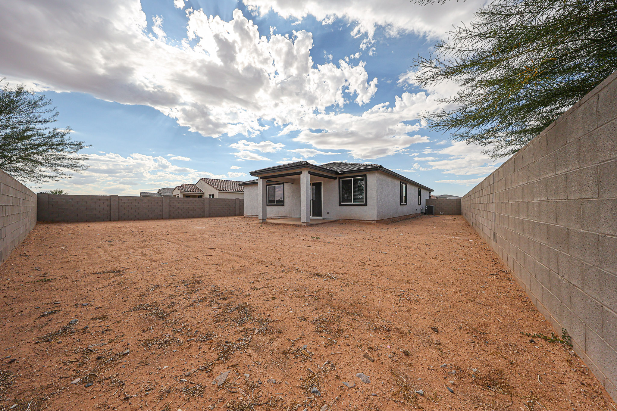 A dirt yard with a house in the background.