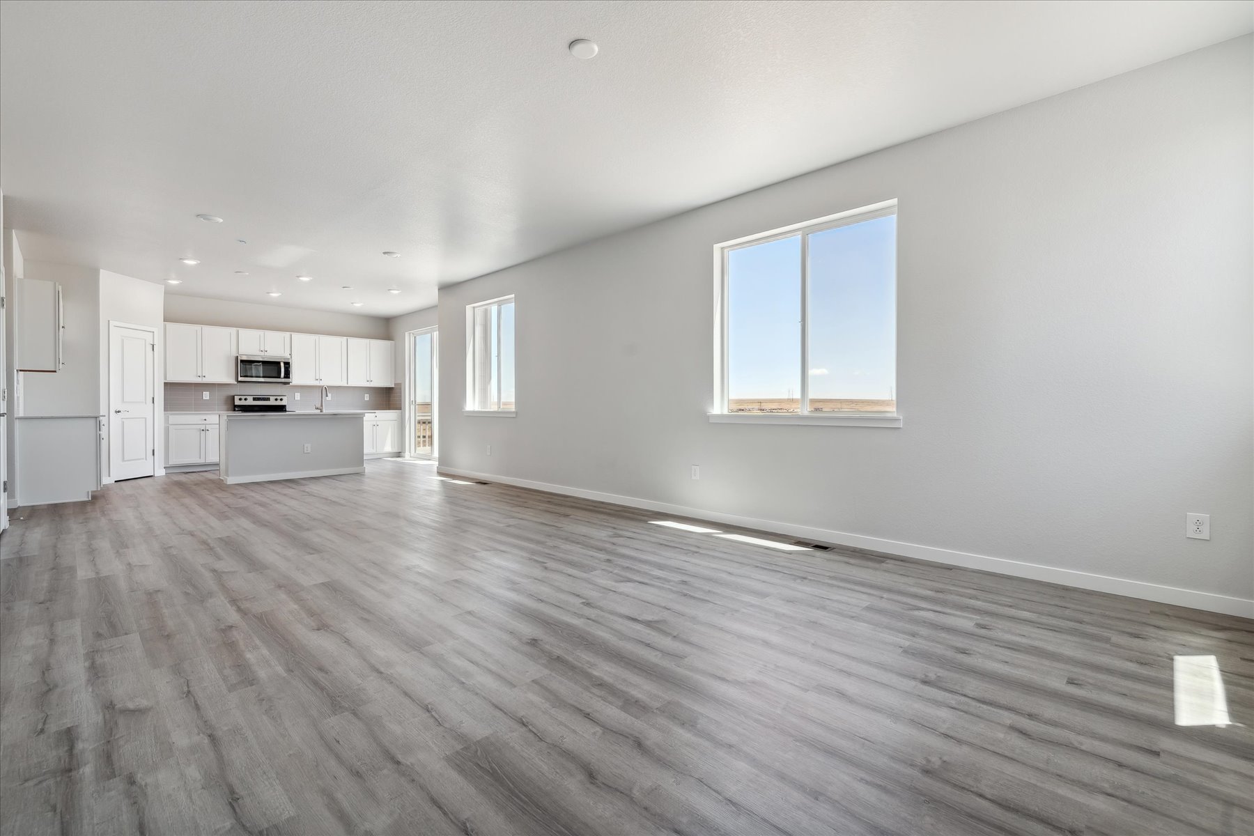 A large empty room with a wood floor and white cabinets.