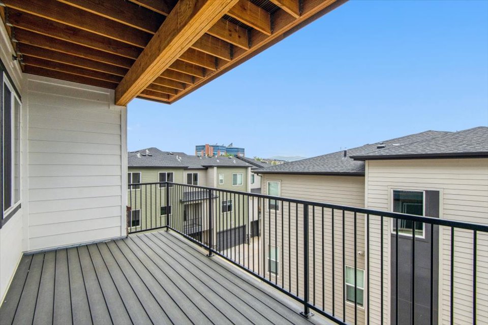 A deck with a railing and buildings in the background.