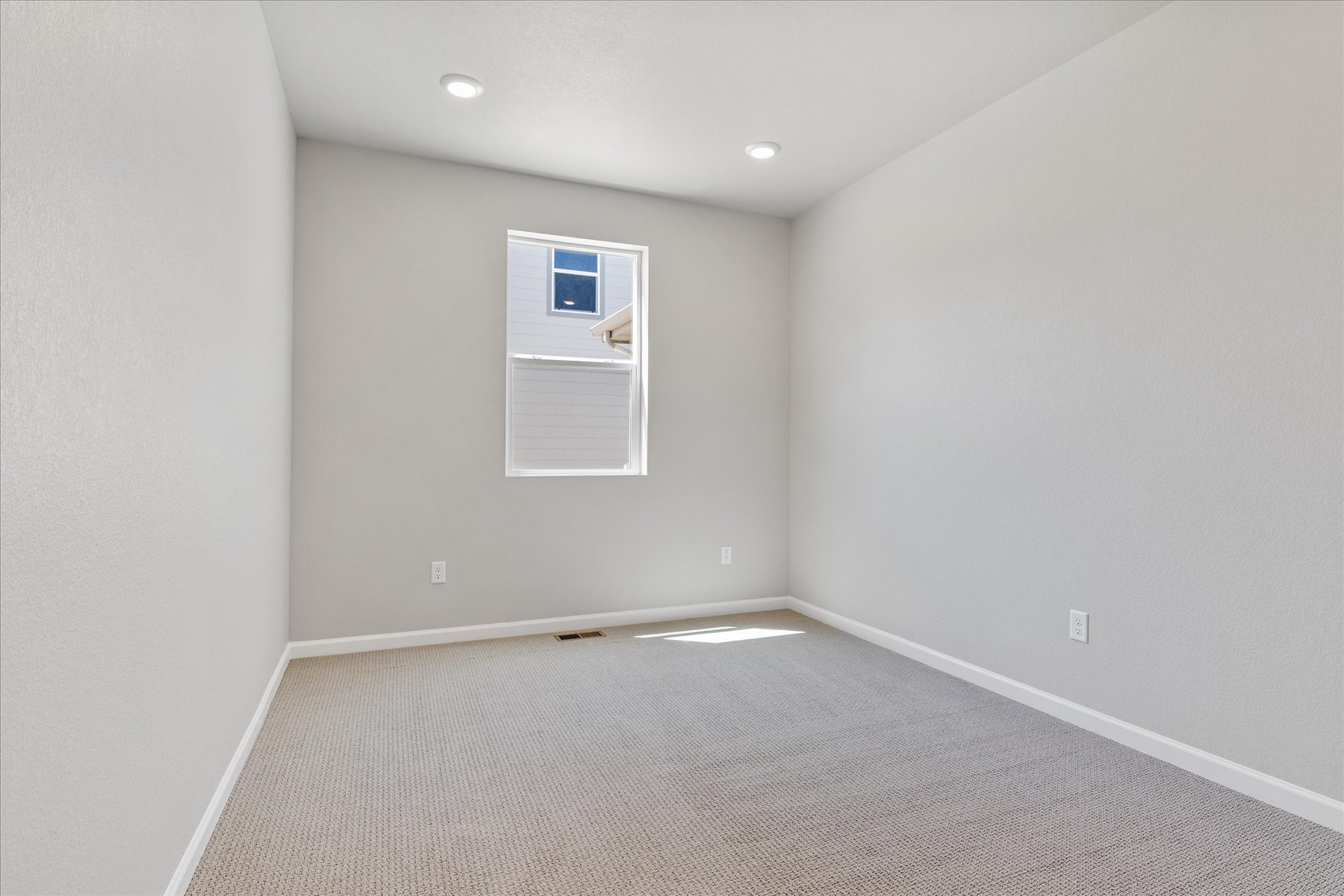 A room with a white wall and a window.