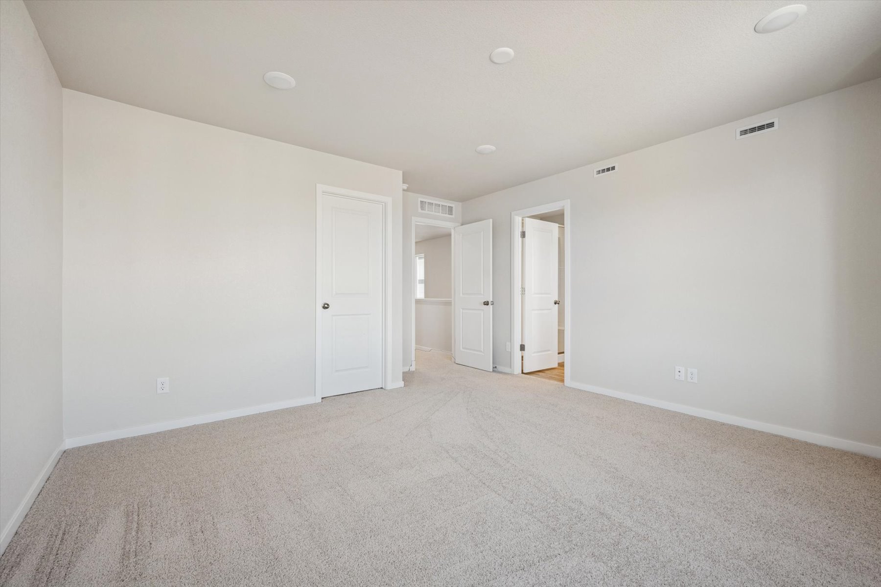 A long hallway with white doors.
