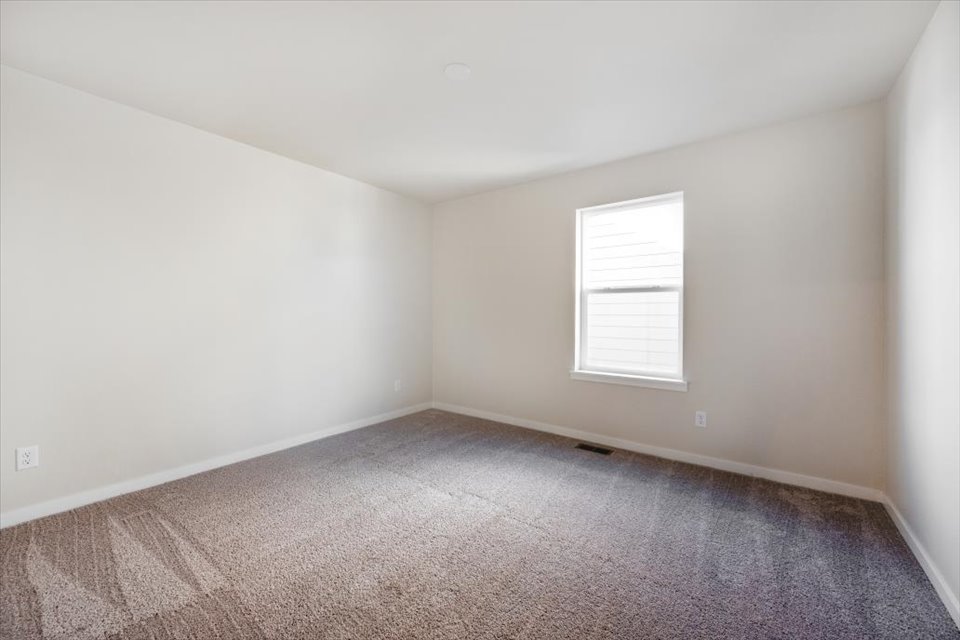 A room with a carpet and a window.