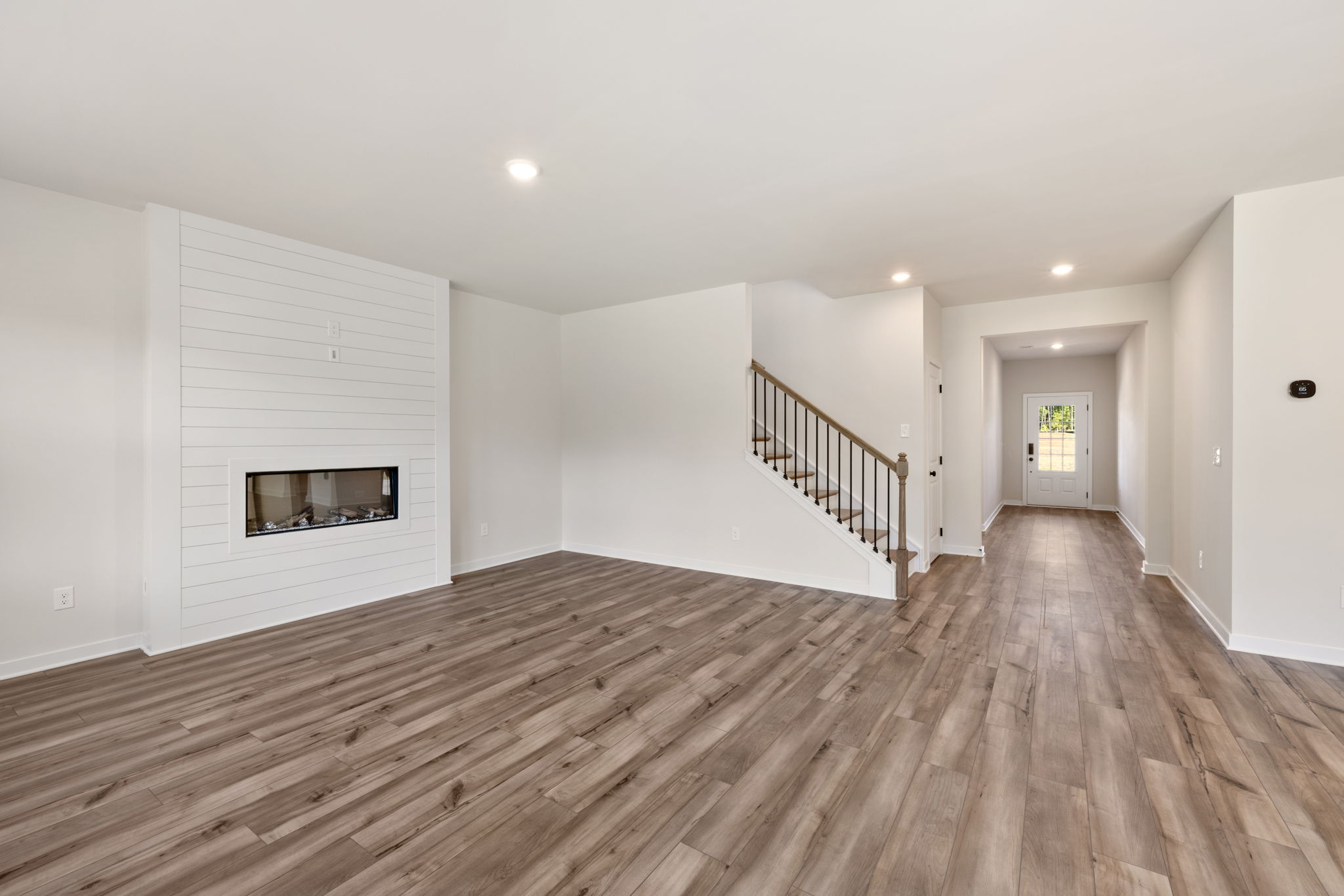 A large empty room with a wood floor and a fireplace.