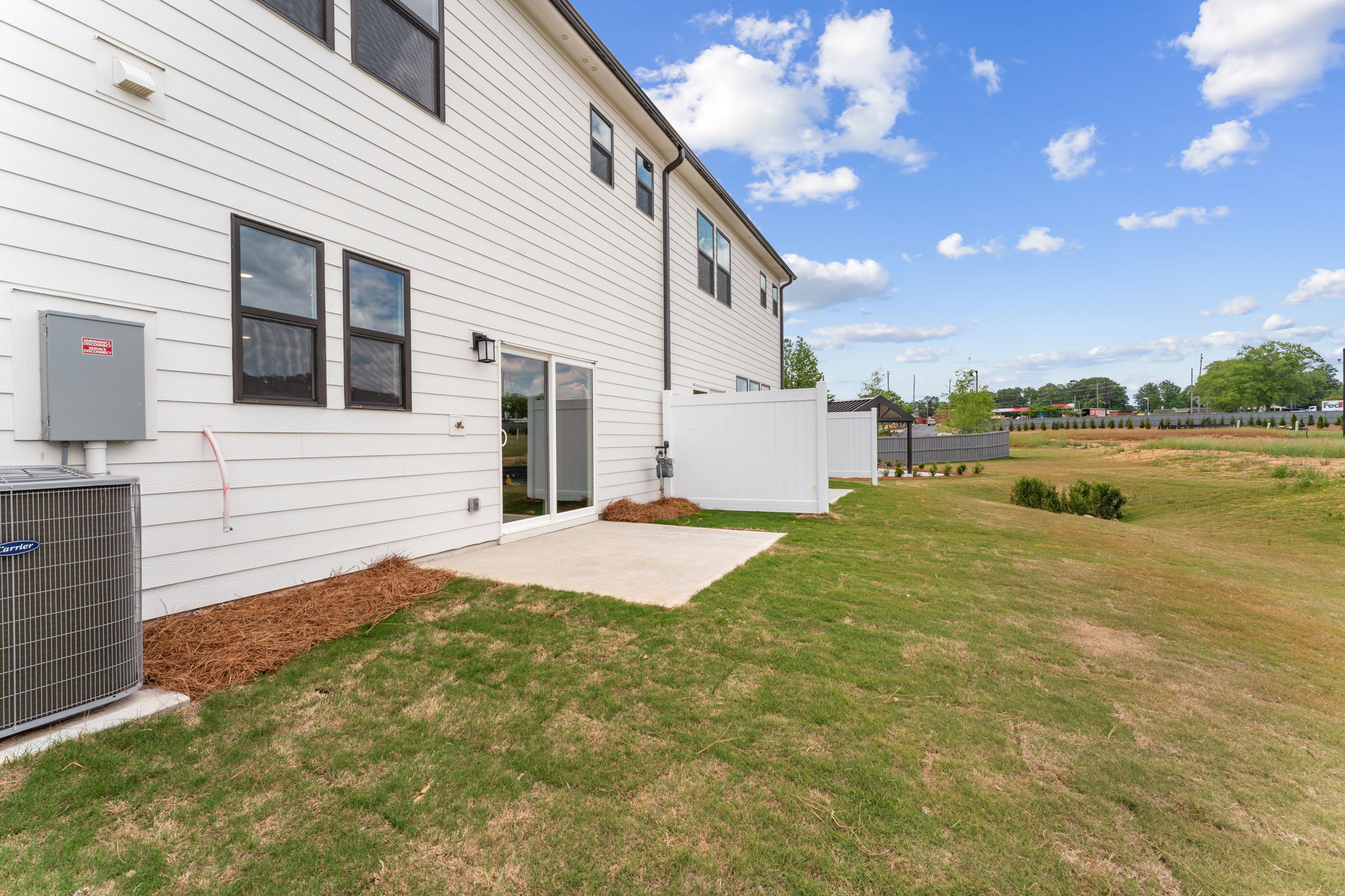A white building with a fence and grass in front of it.