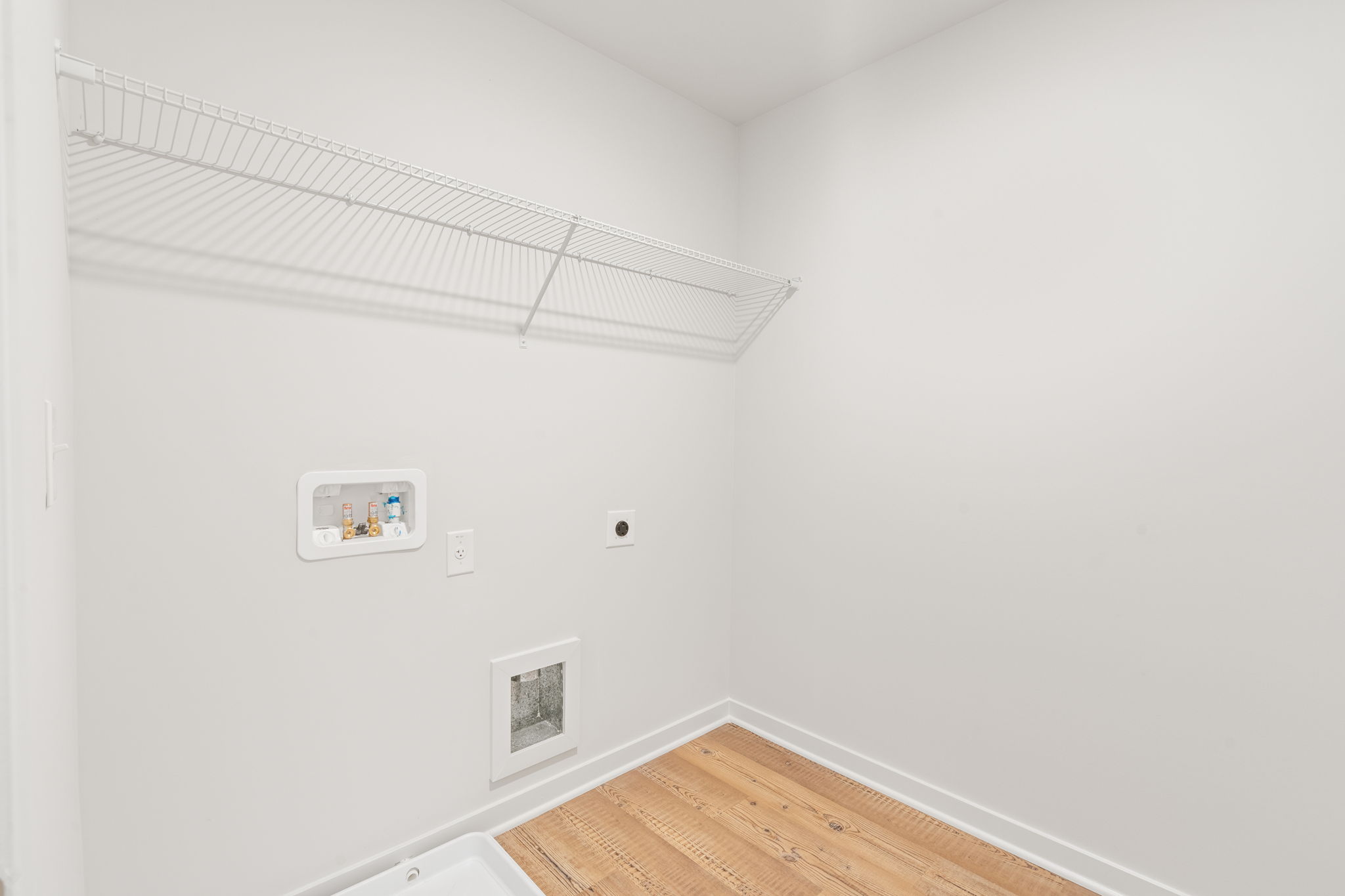 A white room with a wood floor and a white wall with a white ceiling.