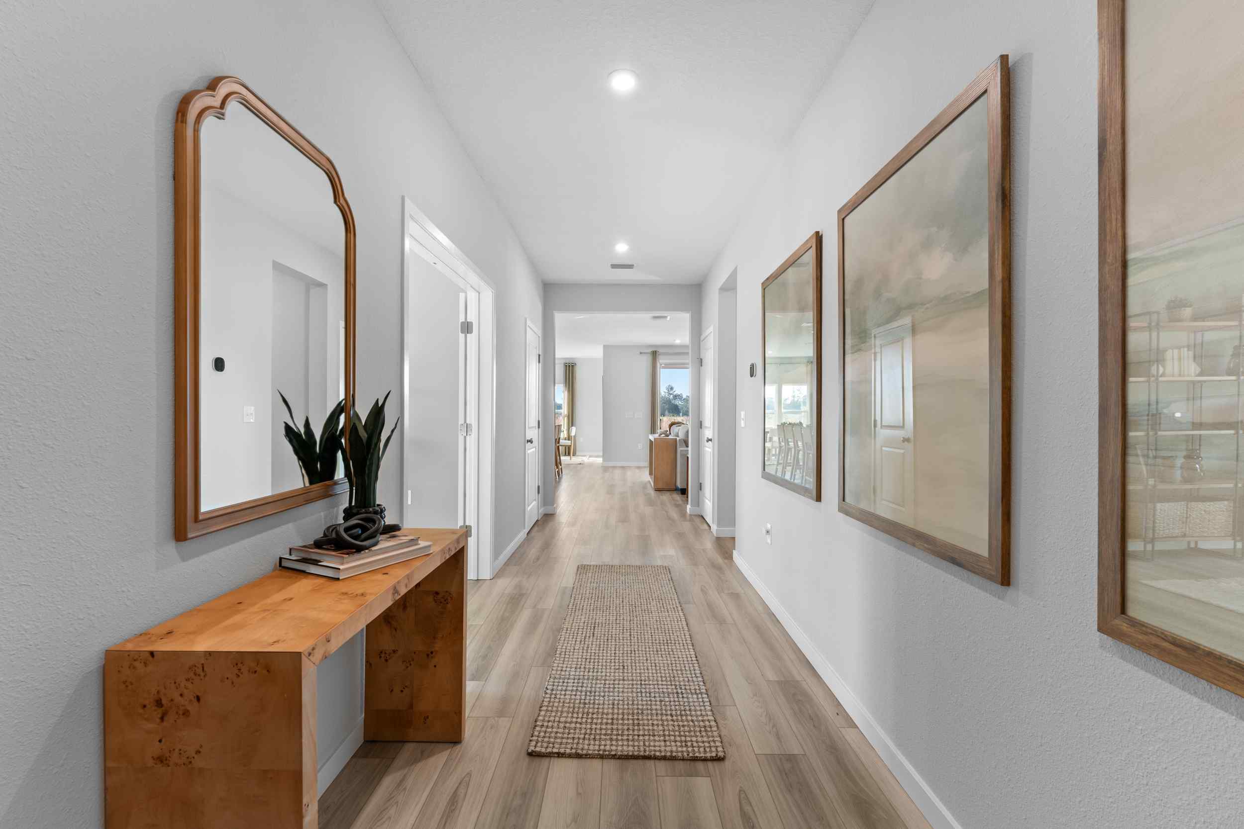 A long hallway with a mirror and a table.