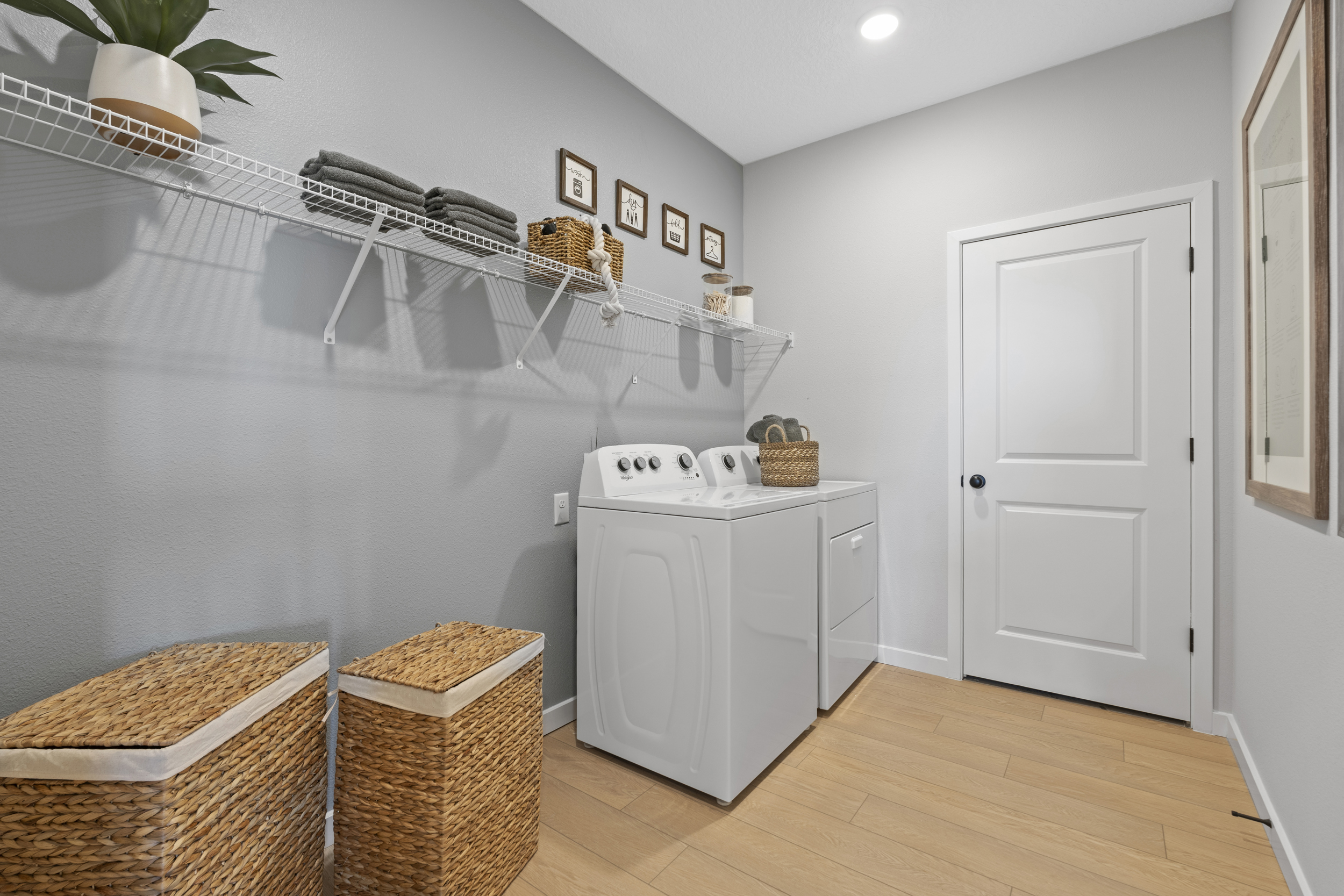 Kenai Model Home Laundry Room with Washer and Dryer and two Basket Hampers at Reserve East in Flagler Beach