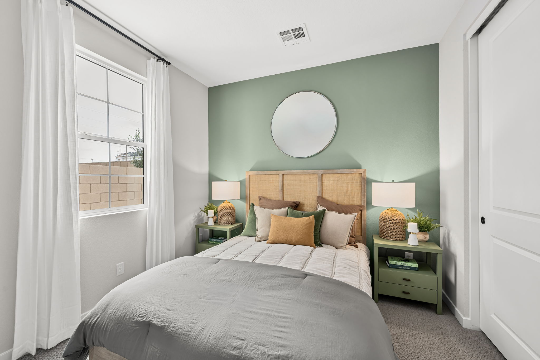 A bedroom with a bed and a mirror.