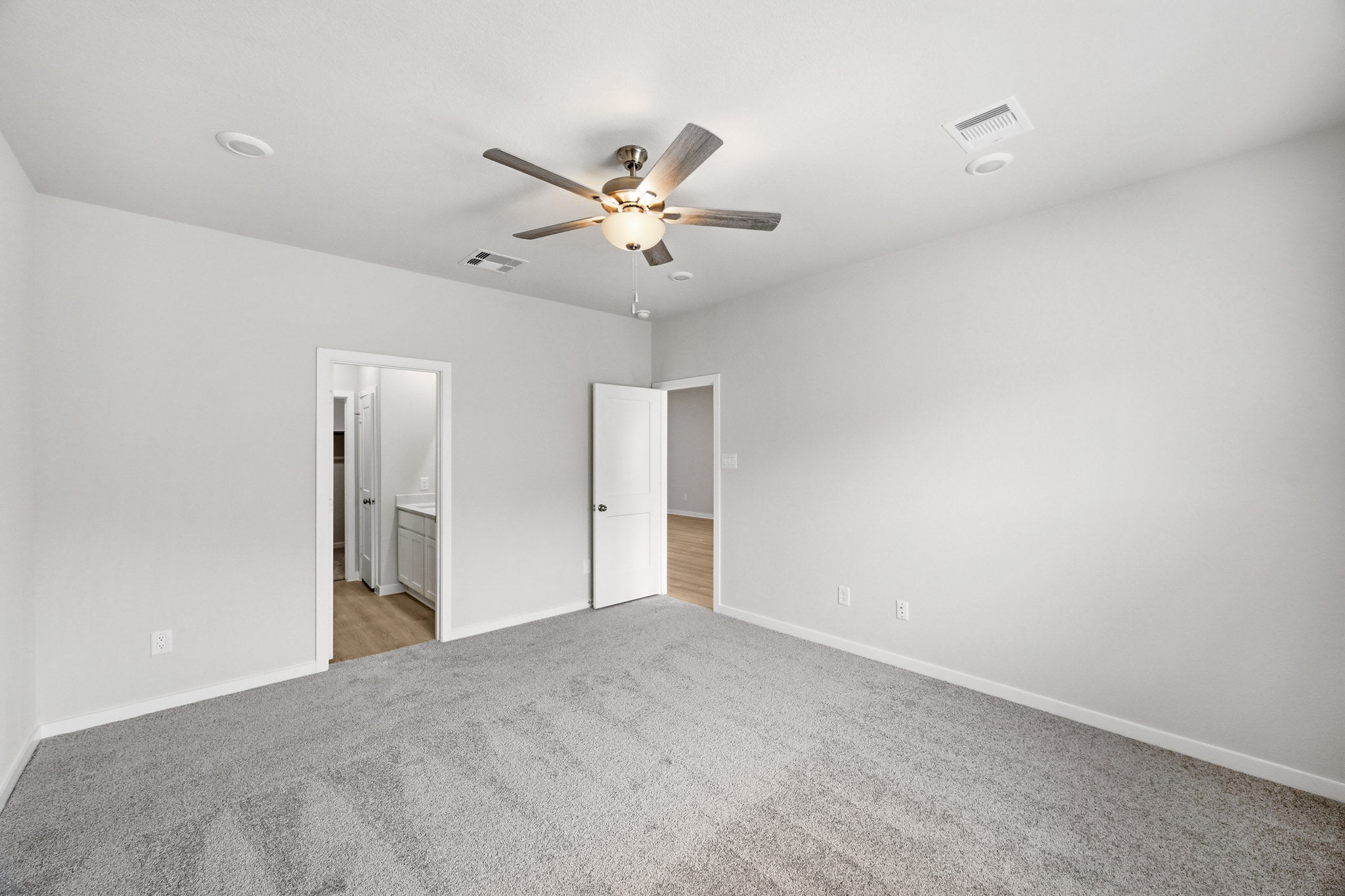 A room with a ceiling fan and a carpet.