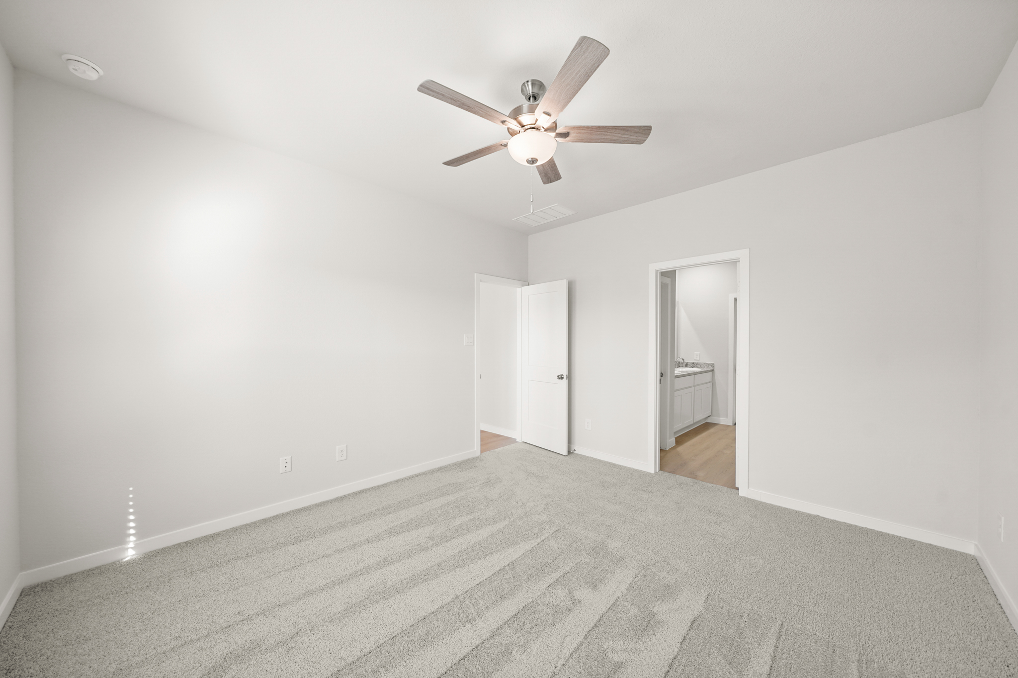 A room with a ceiling fan and a door.