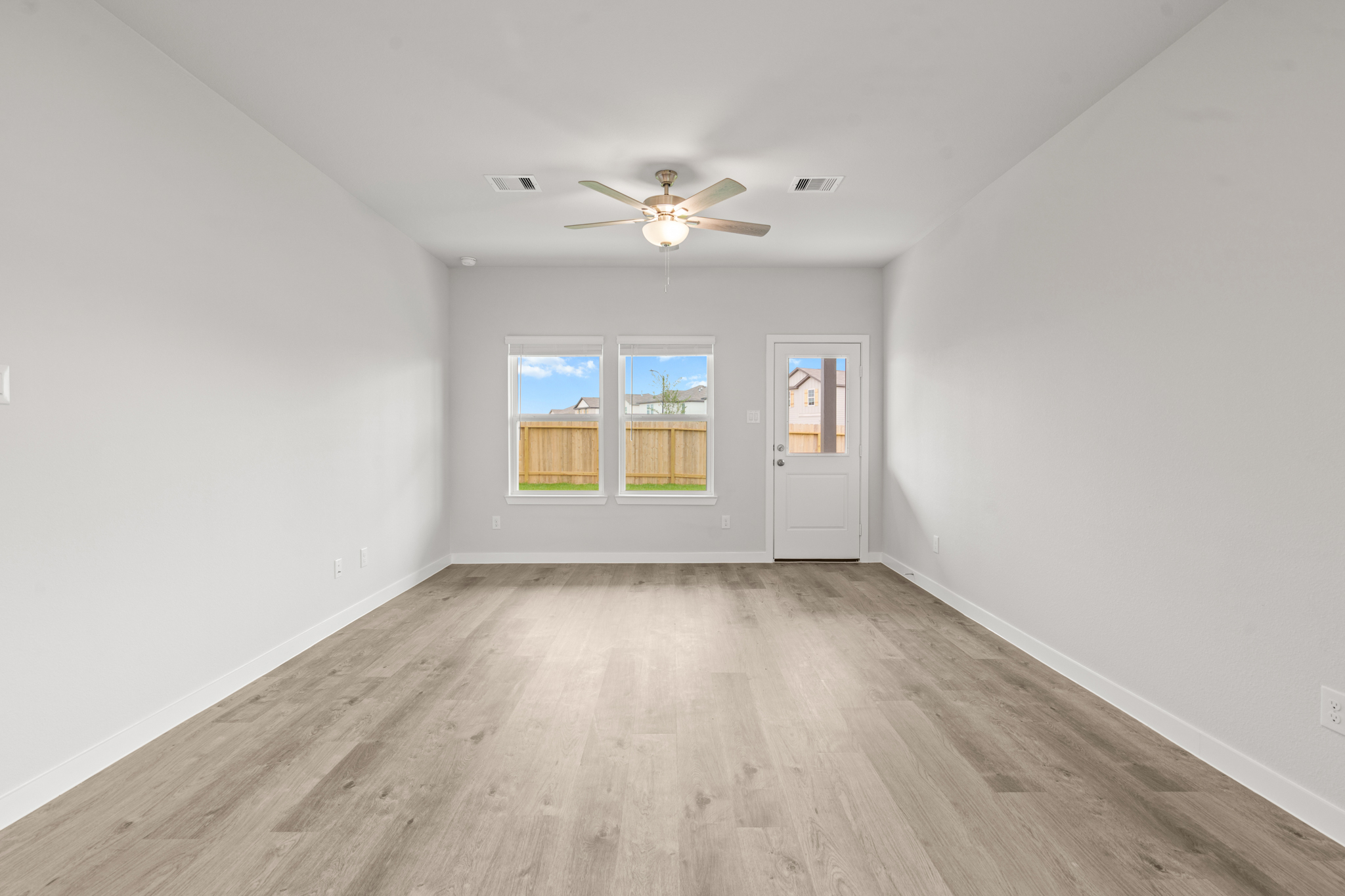 A room with a ceiling fan and a wood floor.
