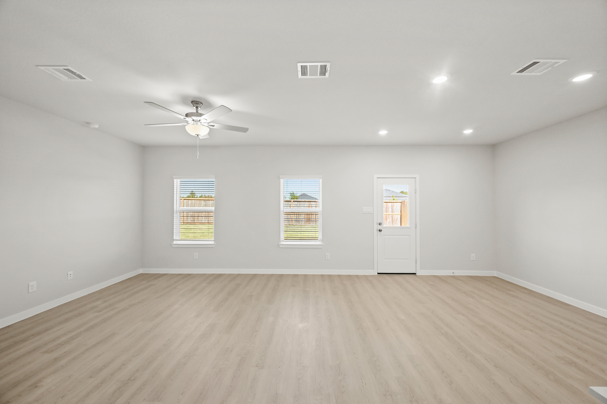 A room with a ceiling fan and a wood floor.