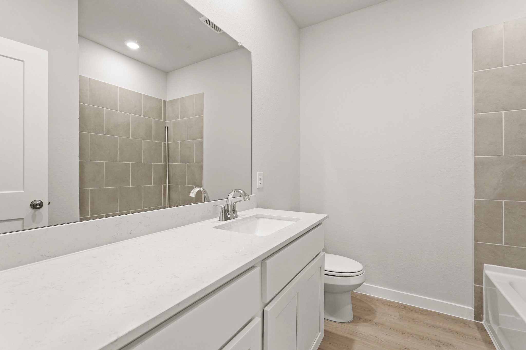 A bathroom with a sink toilet and mirror.
