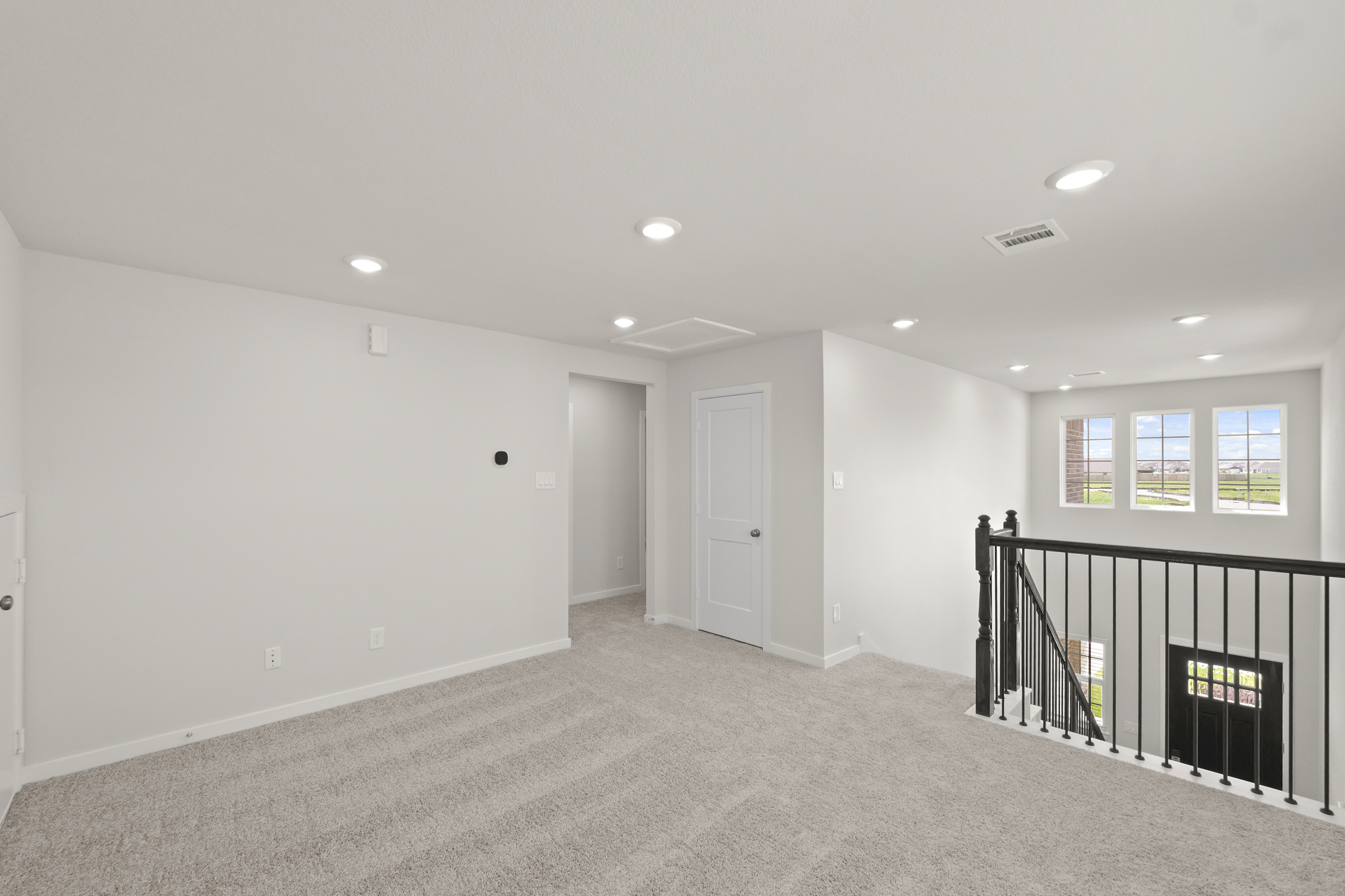 A room with a black railing and white walls.