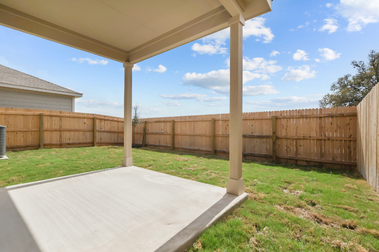 A fenced in yard with a covered area and a wood structure.