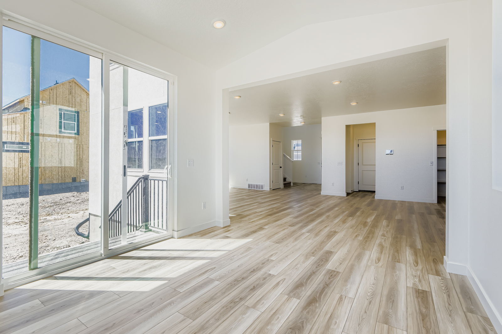 A large empty room with a wood floor and a glass door.