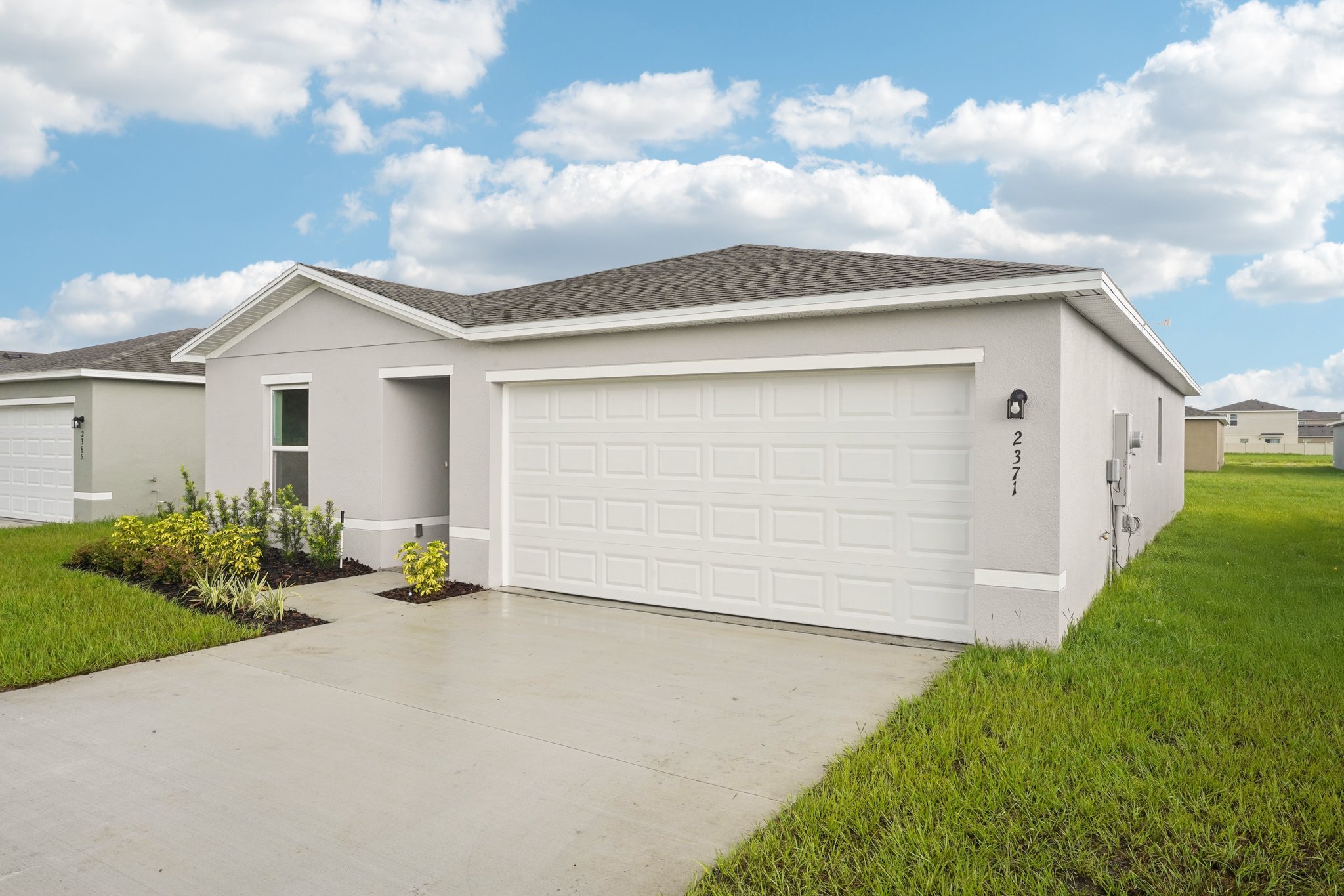 A white garage with a grass lawn.